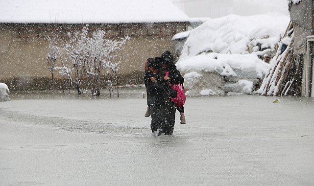 Evinin önünde biriken su nedeniyle çocuklarını sırtında taşıyor