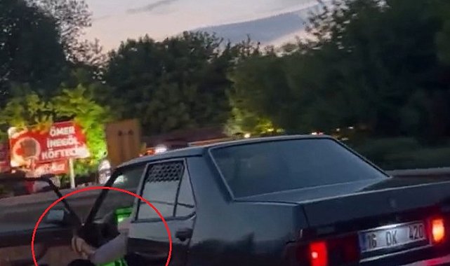 Otomobilinin sol ön kapısını açıp, ayağıyla tutarak trafikte ilerledi