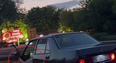Otomobilinin sol ön kapısını açıp, ayağıyla tutarak trafikte ilerledi