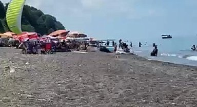 Sahilde motorlu yamaç paraşütüyle havalanırken tatilcilerin arasına daldı