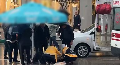Otomobilin çarptığı yaralıyı yağmurdan korumak için şemsiye tuttular