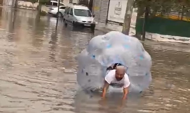 Sağanakta suyla dolan caddede içine girdiği büyük şeffaf balonla ilerledi