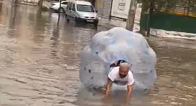Sağanakta suyla dolan caddede içine girdiği büyük şeffaf balonla ilerledi
